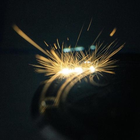Photographie montrant les étincelles jaillissant d'un fond de boîte de montre cependant qu'il subit un gravage laser.